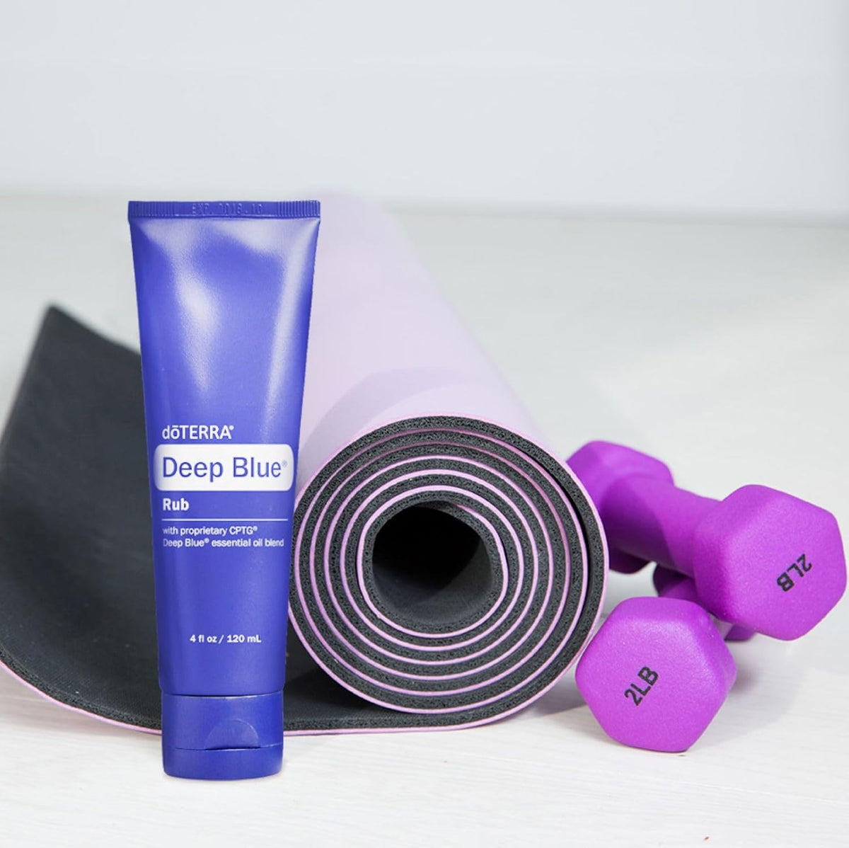 doTERRA Deep Blue Rub 120 mL beside an exercise mat and purple dumbbells